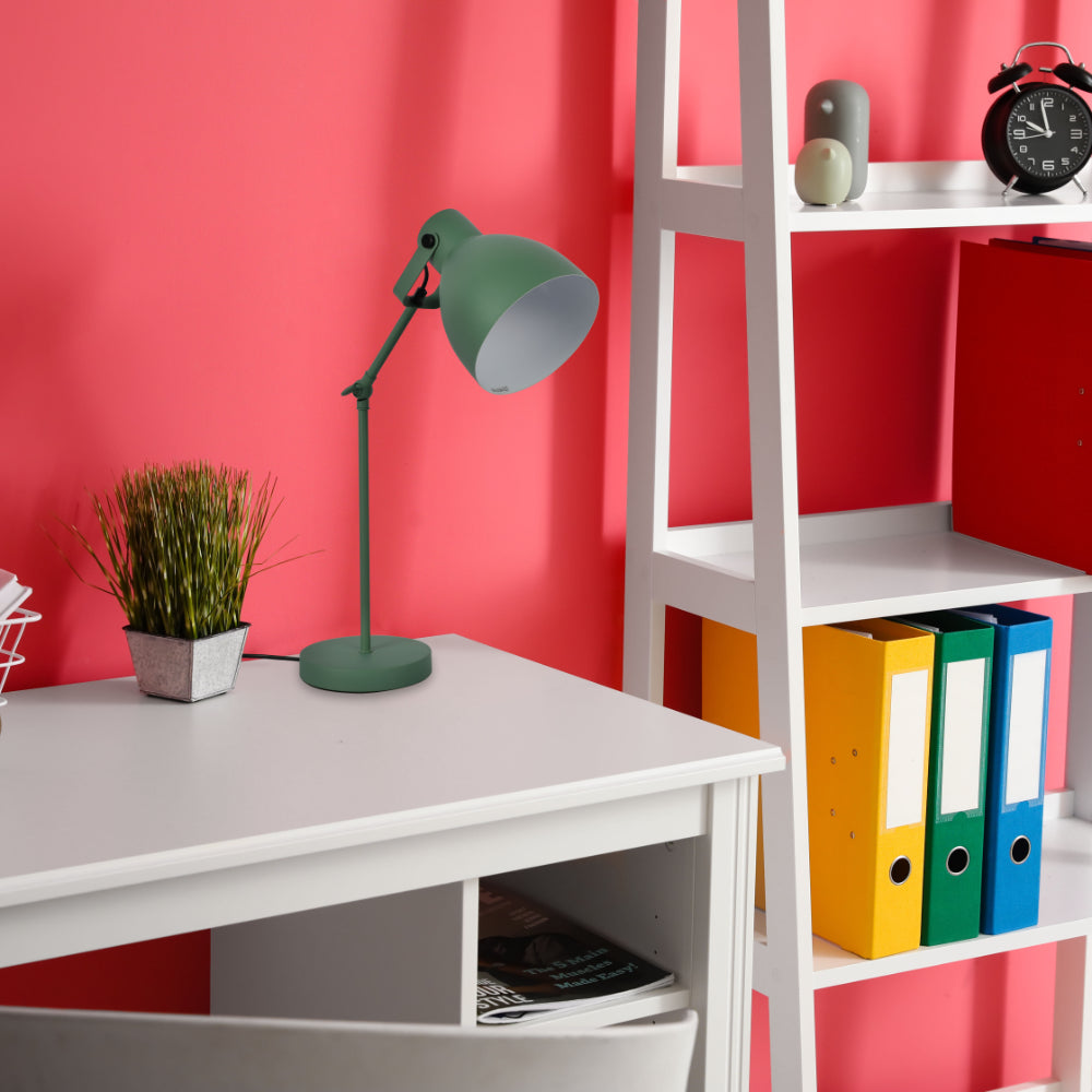 A green desk lamp illuminates a study space. The bright light showcases a modern, minimalist design.