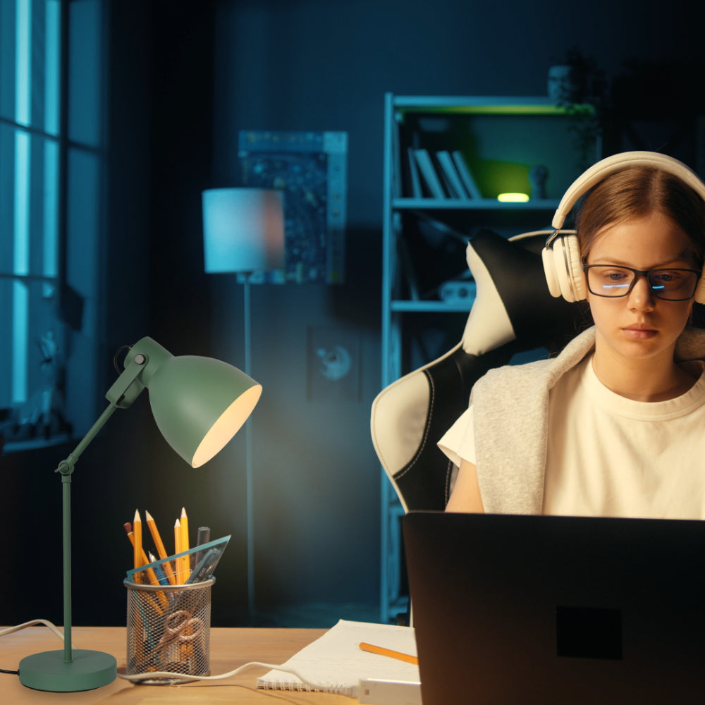 A desk lamp casts a warm glow, contrasting with the cool ambient room lighting for a focused working atmosphere.