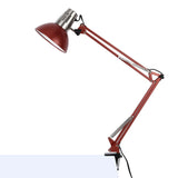 An adjustable desk lamp, with a red shade and articulated arm, clamped to a desk, providing focused task lighting.