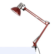 An adjustable desk lamp, with a red shade and articulated arm, clamped to a desk, providing focused task lighting.