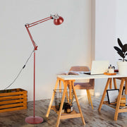 A red adjustable floor lamp illuminates a bright home office space, showcasing modern and practical lighting.