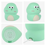 A mint green, cartoon dinosaur night light with white features and a white cable inserted at the base. The base includes the on/off switch.