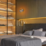 Wall-mounted lighting shines above a bed in this lifestyle shot, creating a warm and inviting atmosphere.