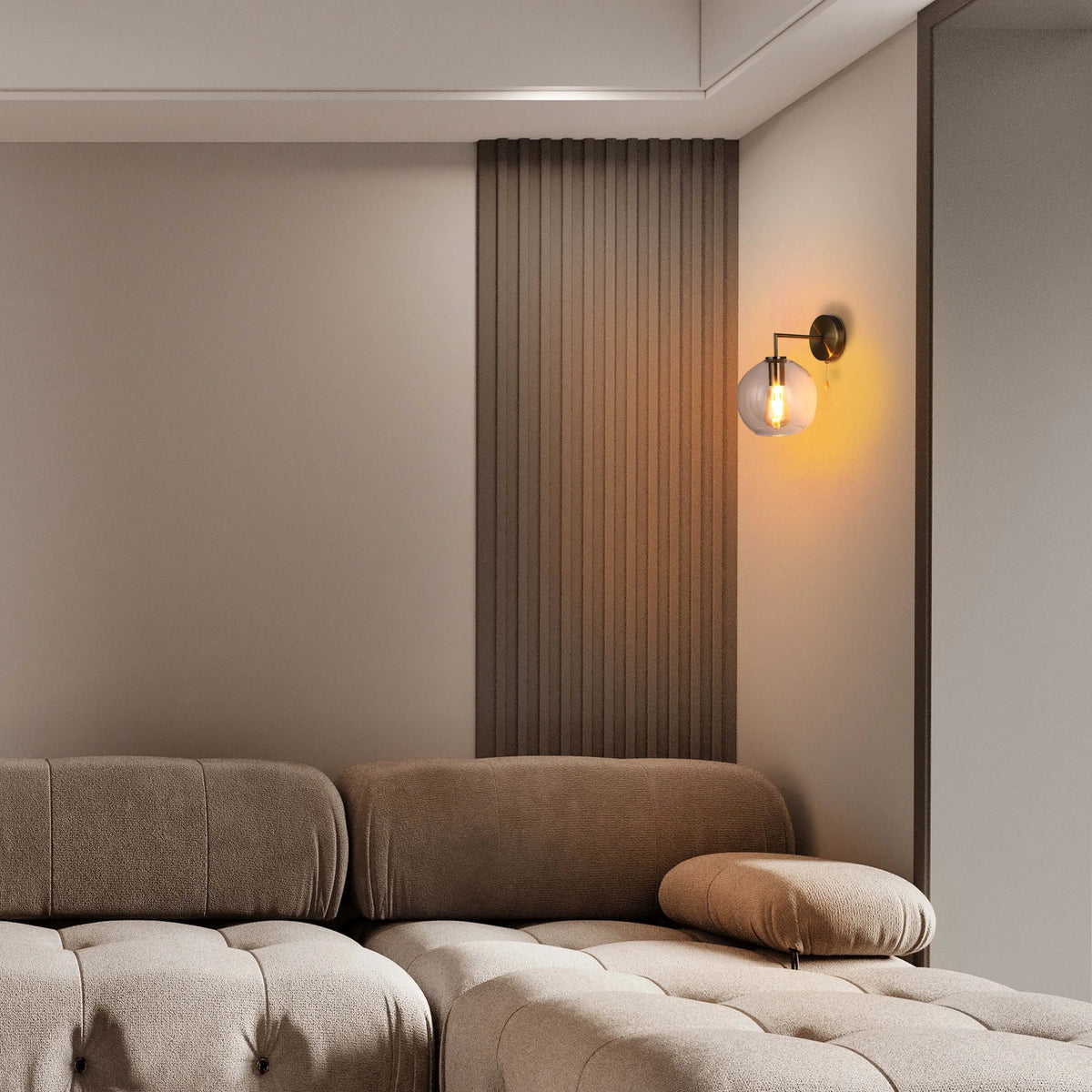 A wall mounted light fixture emits a warm glow from a clear globe. The base is a metallic bronze.