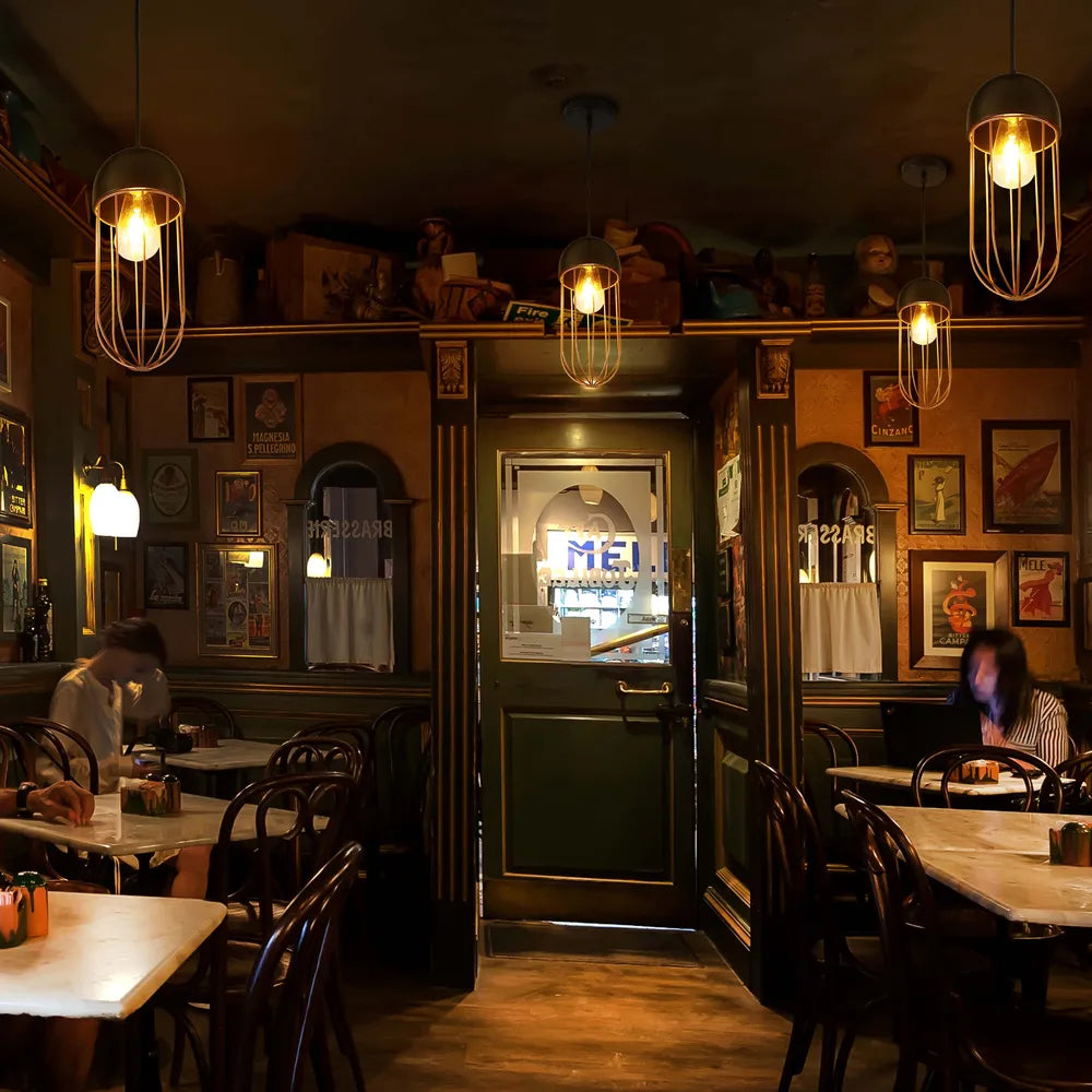 Stylish metal pendant light in black and gold, enhancing a modern dining area with its cage design and elegant ambiance.150-180820