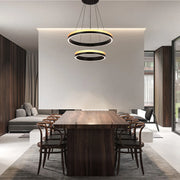 A contemporary two-tier ring pendant light hangs above a dark wood dining table, creating a modern and inviting atmosphere.
