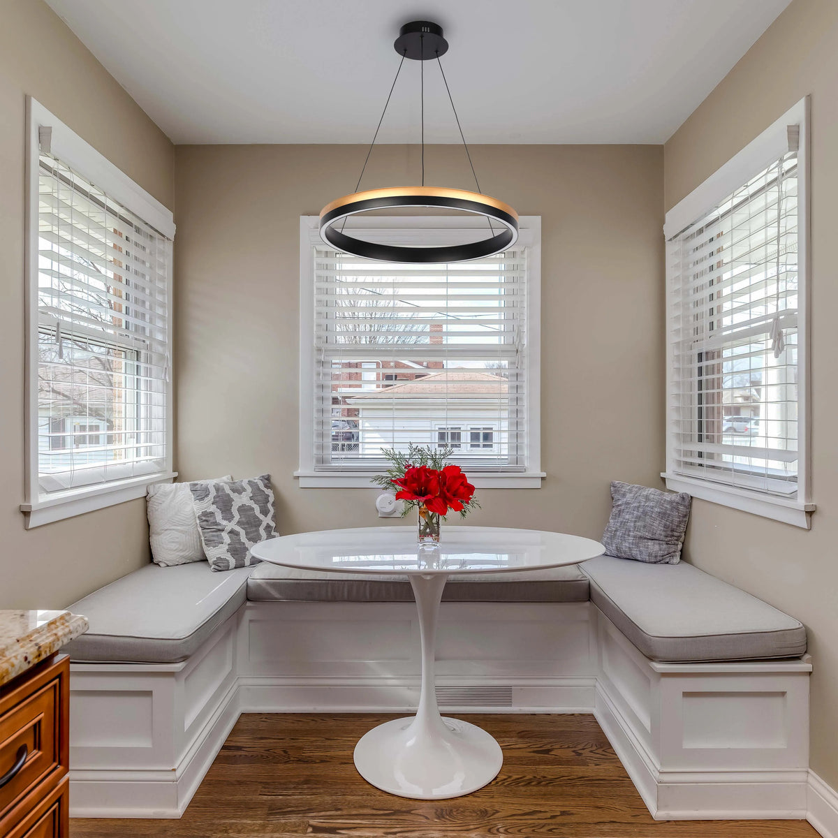 A modern, ring-shaped pendant light is the focal point above a breakfast nook, offering ambient illumination and a sleek design aesthetic.