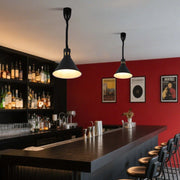 Contemporary black pendant lights illuminate a stylish bar, casting a warm glow over the counter and creating an inviting atmosphere.