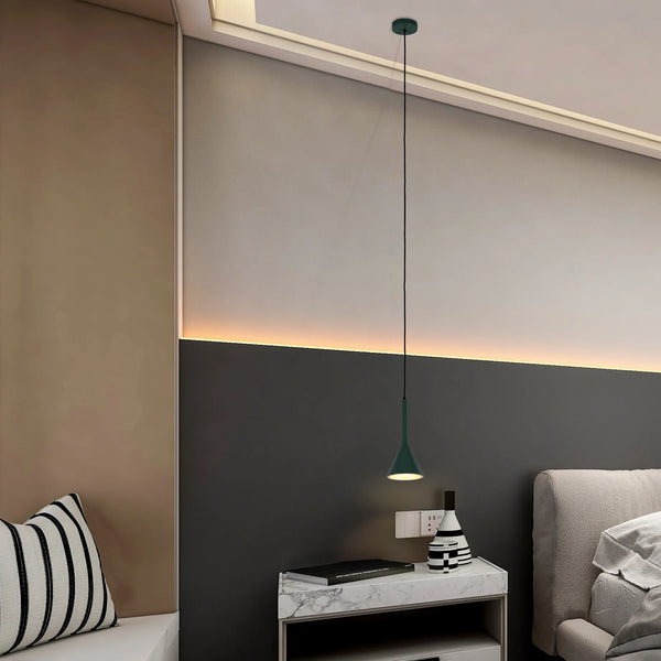 A modern interior features a stylish pendant light, casting a warm glow over a bedside table with monochrome decor.