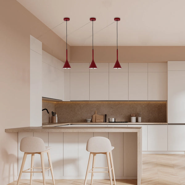 Three red pendant lights hang above a kitchen island. Modern design for stylish kitchen lighting.