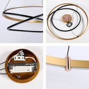 A modern, circular pendant light with gold, black and white rings. The light fixture has a minimalist and contemporary design.