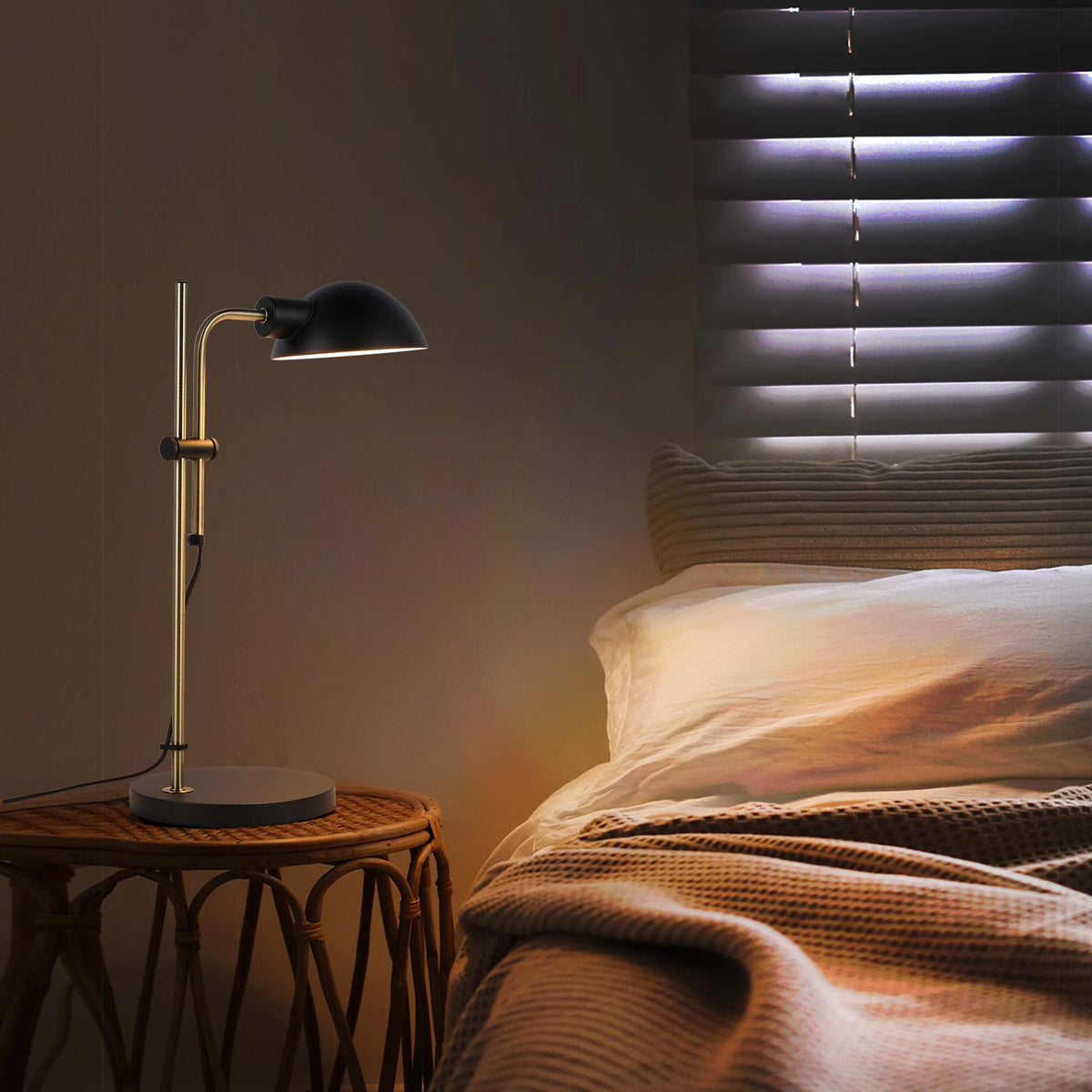 Bedside lamp illuminating the bedroom with its warm, focused light. Blinds diffuse light, creating a relaxing ambience.