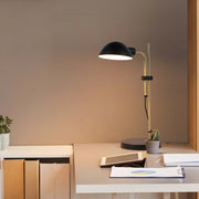 A contemporary desk lamp illuminates a workspace with a warm glow, highlighting documents and adding a touch of modern elegance.