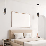 Contemporary bedroom featuring two suspended geometric lamps. The lighting fixtures are black with an exposed bronze shade.