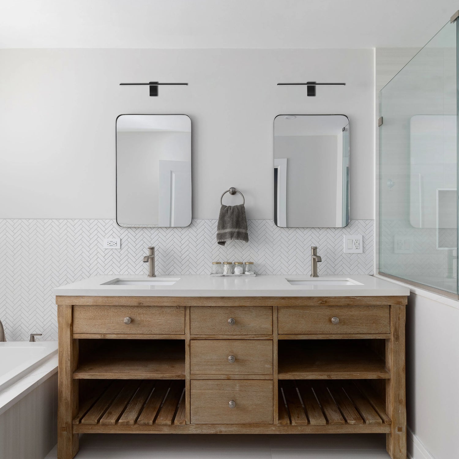 Two contemporary black light fixtures above twin mirrors illuminate this bathroom vanity with a light, stylish touch.