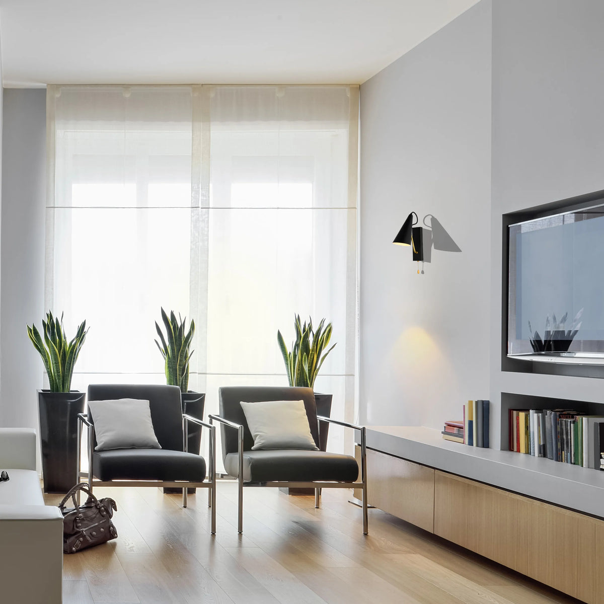 Contemporary lighting: a wall-mounted sconce provides warm accent lighting in a modern living room with natural light from large windows.
