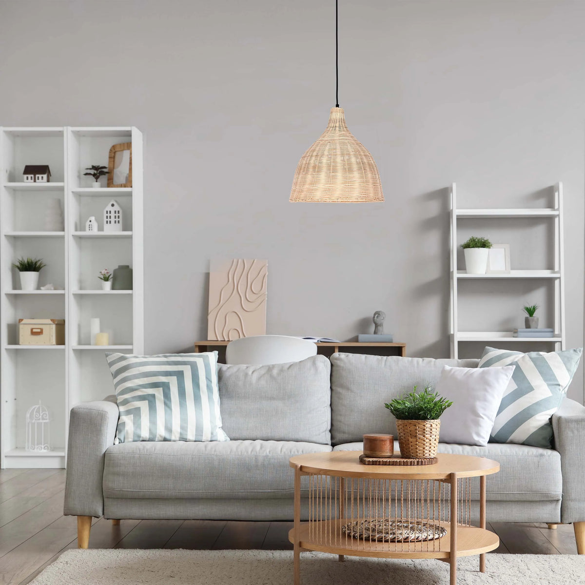 A rattan pendant light hangs above a living space with a grey sofa and light wood coffee table, creating a soft, inviting glow.