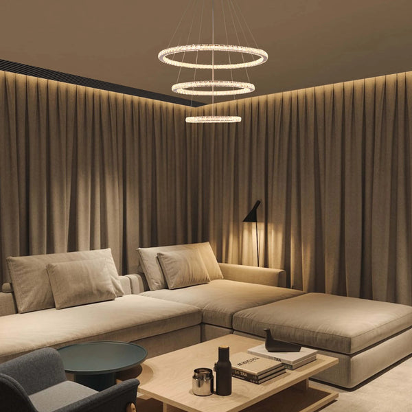 A contemporary multi-tiered ring chandelier, crafted with sparkling crystals, illuminates a modern living space with ambient light.