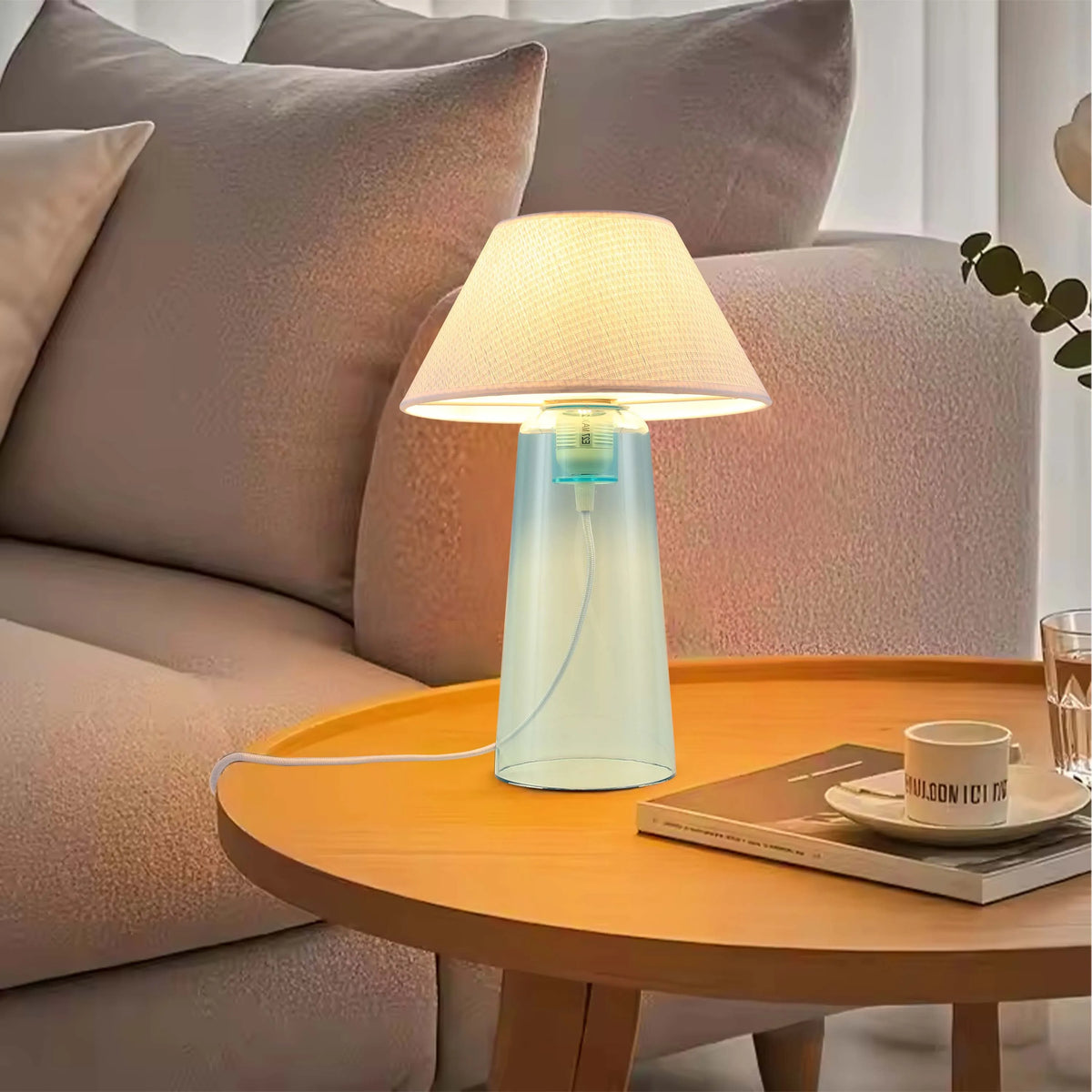 A table lamp with a soft, inviting glow sits on a wooden side table, adding a touch of cosiness to the living room ambiance.
