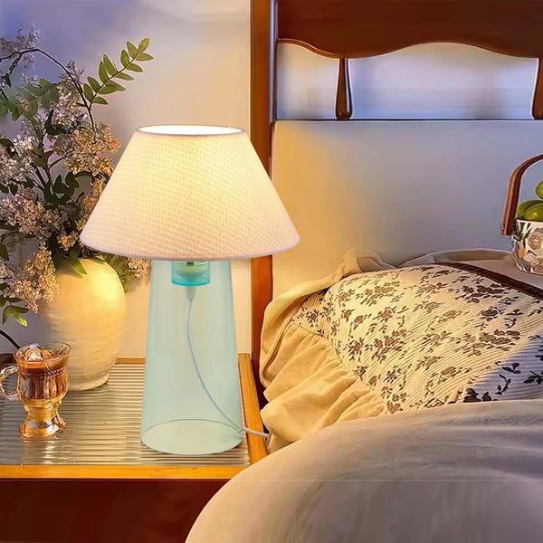 A bedside table lamp emits a soft, warm glow, creating a cosy and inviting atmosphere in a bedroom setting.