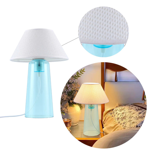 A modern table lamp with a white shade and a blue, transparent base, providing ambient lighting.