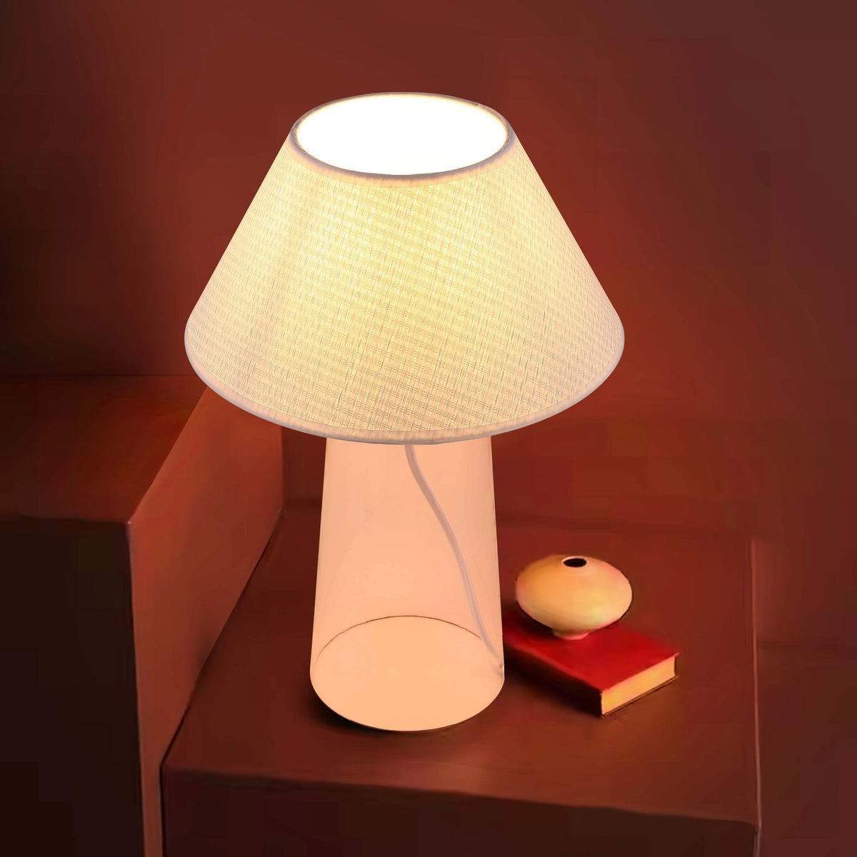 A warm, ambient lighting setup with a modern lamp, red book and decorative spherical object, casting a soft glow on the scene.