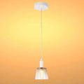 A modern pendant light fixture with a smoked glass shade and white fitting, suspended by a silver cable against a warm gradient backdrop.