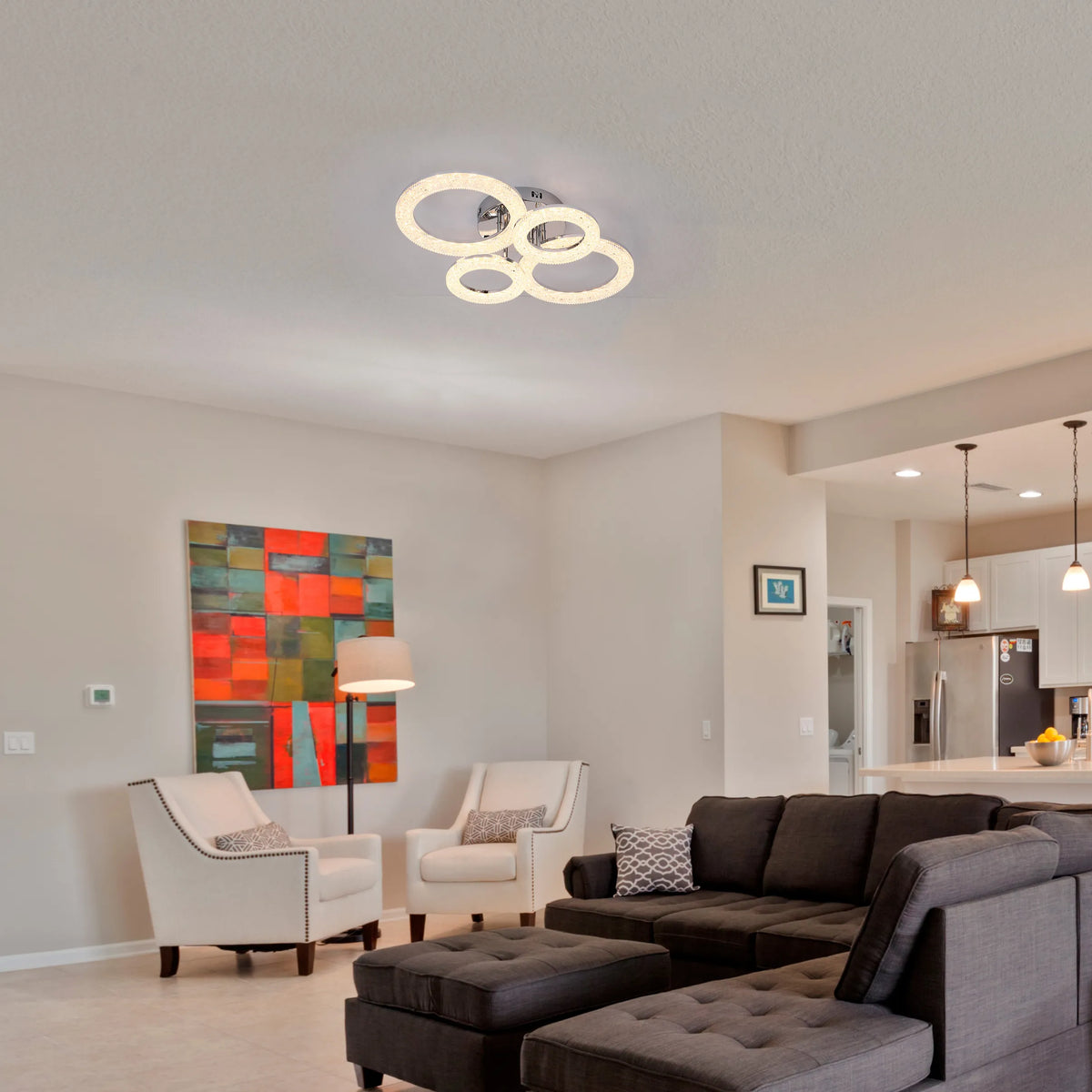 A modern, circular LED ceiling light fixture is the focal point, complemented by pendant lights over the kitchen island.