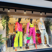 A window display features track lighting illuminating colourful mannequins and clothing, creating a bright and vibrant shopping experience.