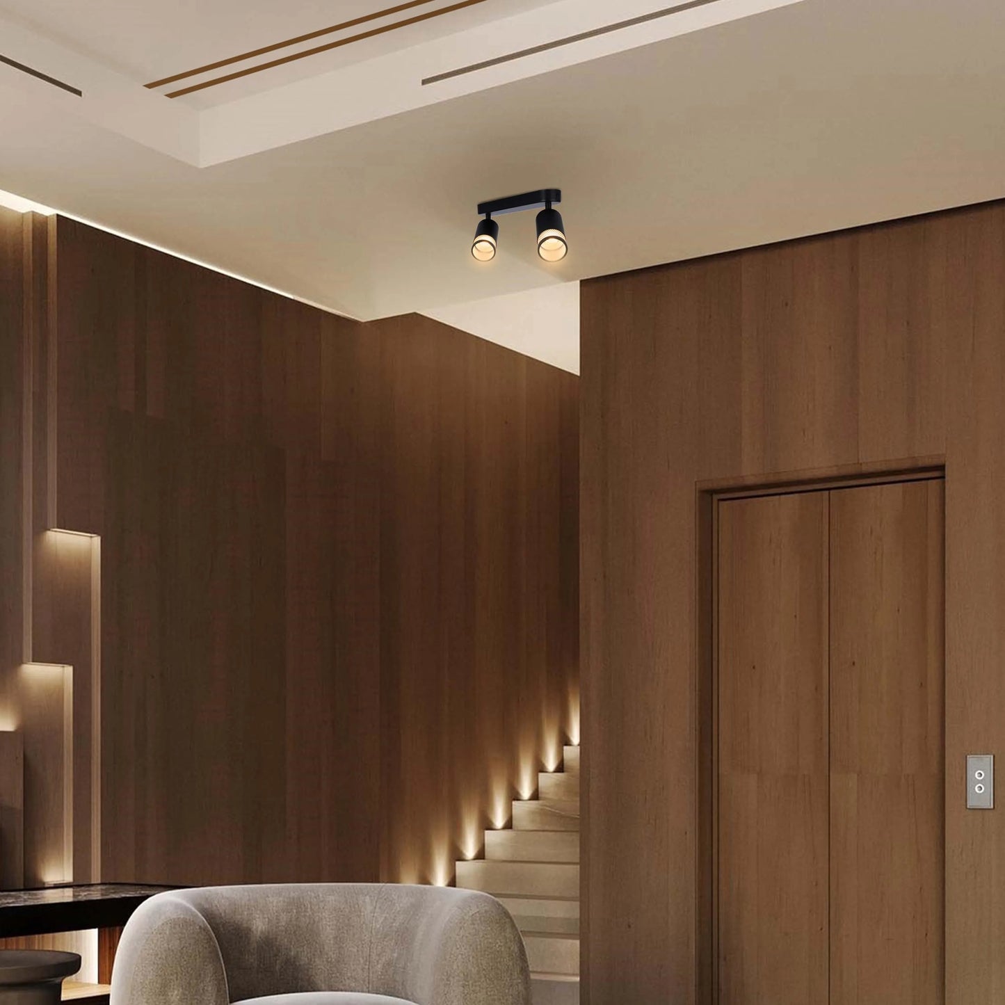 Contemporary interior lighting, with a sleek, black track light fixture illuminating the modern space. The stairwell is softly lit.