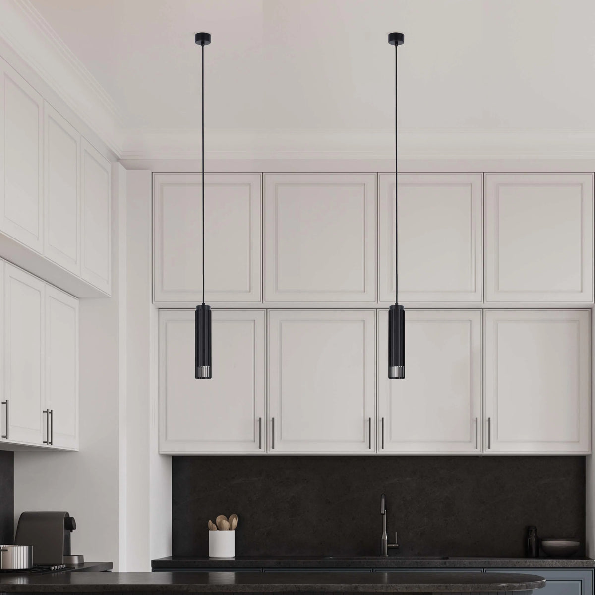 Two pendant lights with black cylindrical shades hang above a modern kitchen island, adding a touch of elegance and focused illumination.