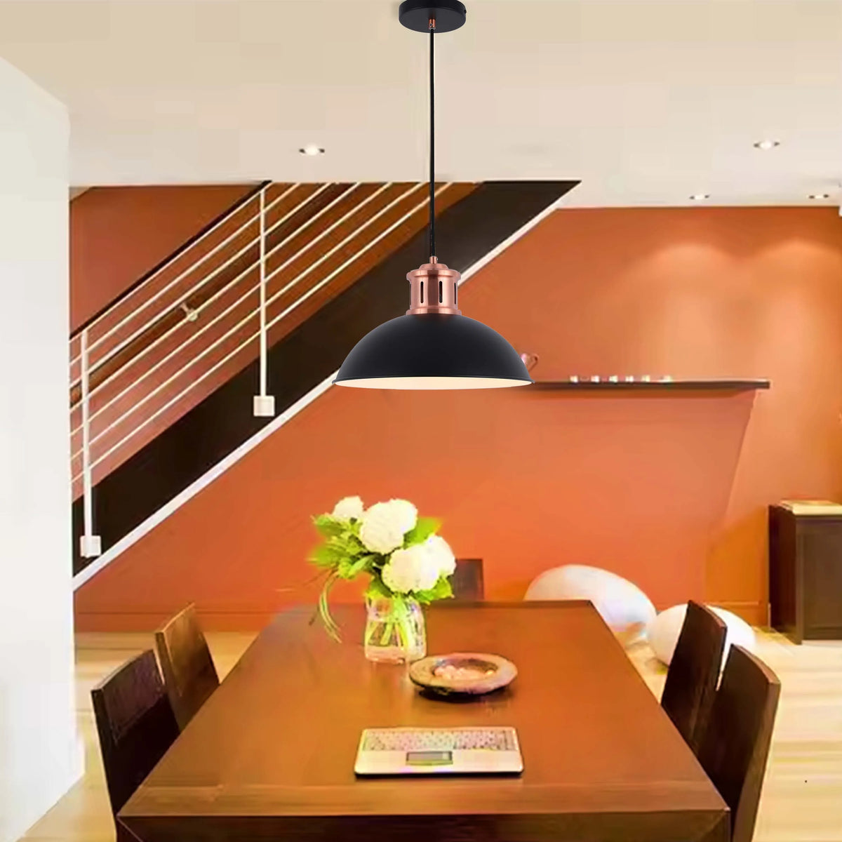 A black and copper pendant light shines bright above a wooden dining table. Modern design with an industrial edge.