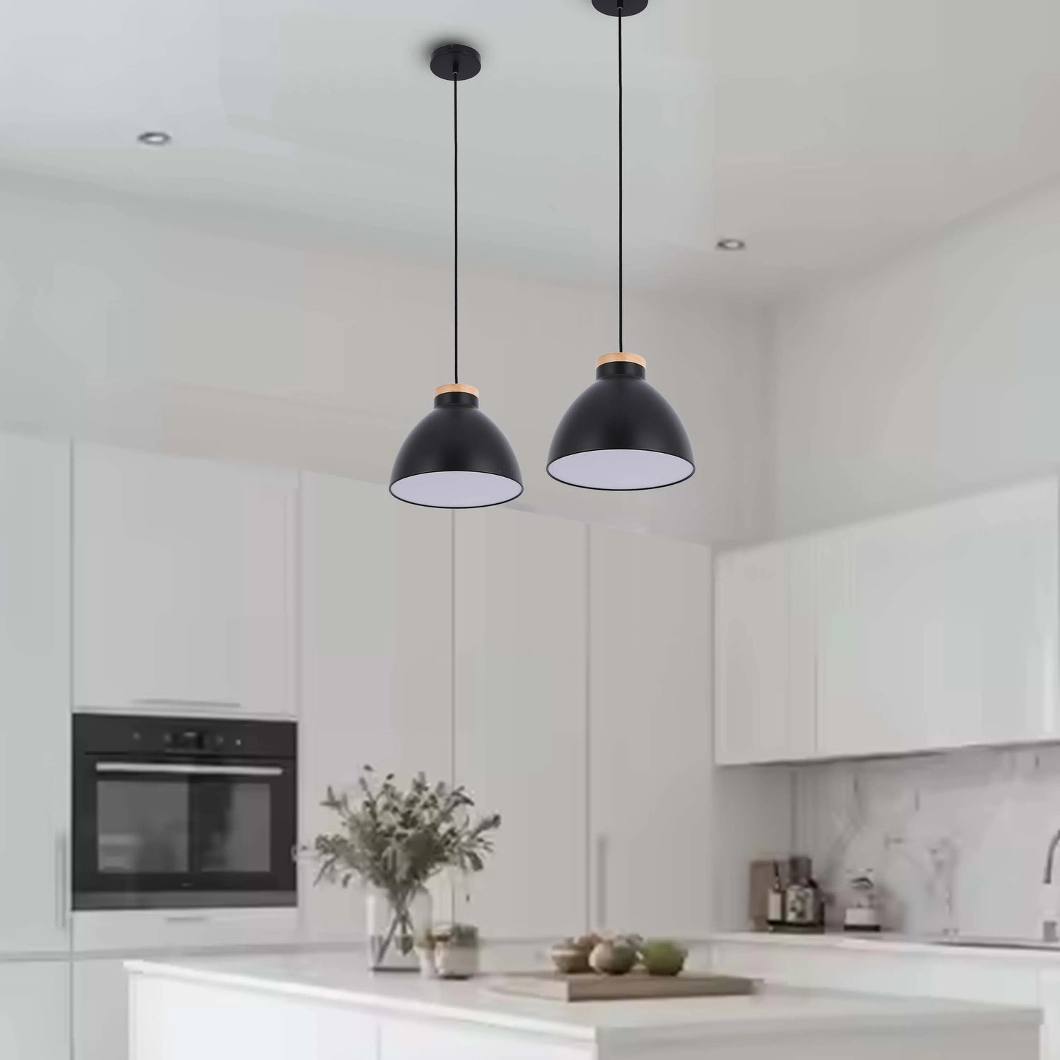 Two black dome pendant lights with wooden accent hang above a kitchen island, adding a touch of modern style to the bright, white space.