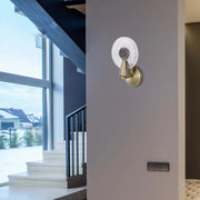 A decorative wall light, featuring a crystal-like design and gold fixture, illuminates a modern hallway with natural light from a window.