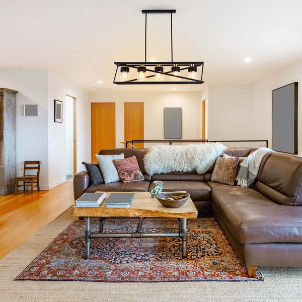 A modern, rectangular chandelier hangs above a cosy living room. The fixture has five bulbs and a matte black finish.