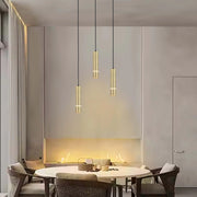 Stylish gold pendant lights hang above a dining table with a lit recessed fireplace behind in a modern dining room.