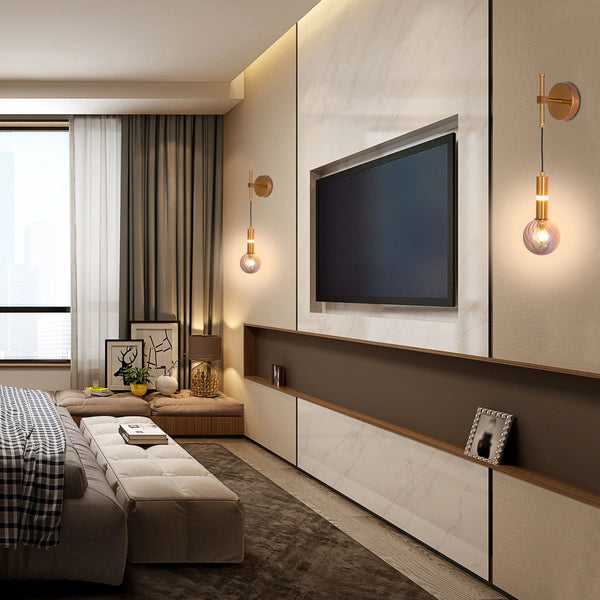 Bedroom lighting: two gold wall lights with decorative glass globes flank a wall-mounted television in a modern bedroom.