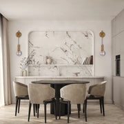 Stylish wall sconces illuminate this elegant dining space. Gold fittings hold glass globes, casting a soft, ambient light.