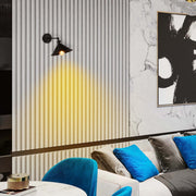 A black wall light is illuminated, casting a warm, directional glow on the textured white wall behind it.