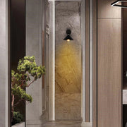 A hallway features a wall sconce emitting a warm glow. An ambient modern light is also visible in the right corner.
