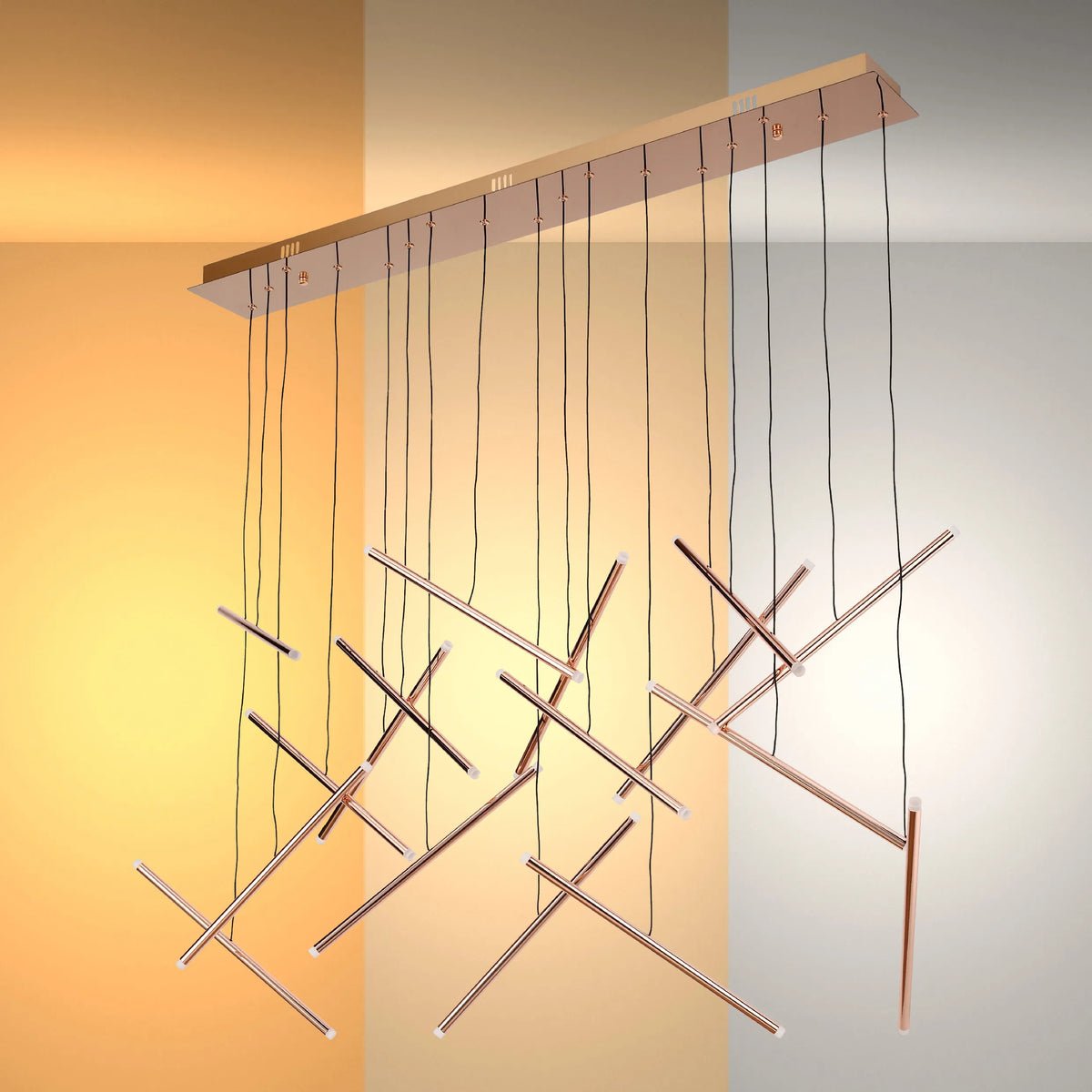 A stylish rose gold pendant light with thin, intersecting tubes suspended from a rectangular ceiling plate by delicate black cables.