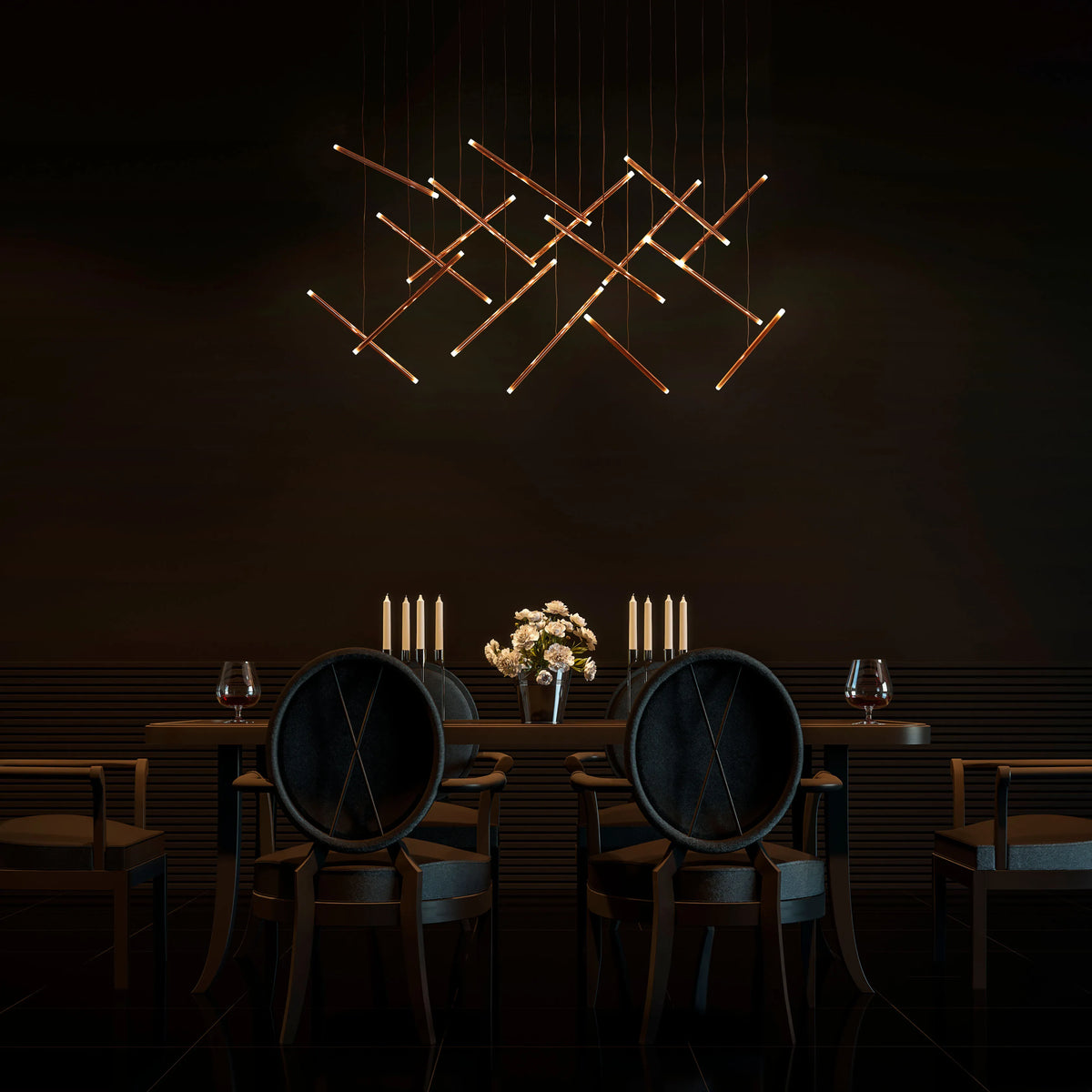 A modern chandelier made of interconnected golden rods provides ambient lighting above a dimly lit dining table.