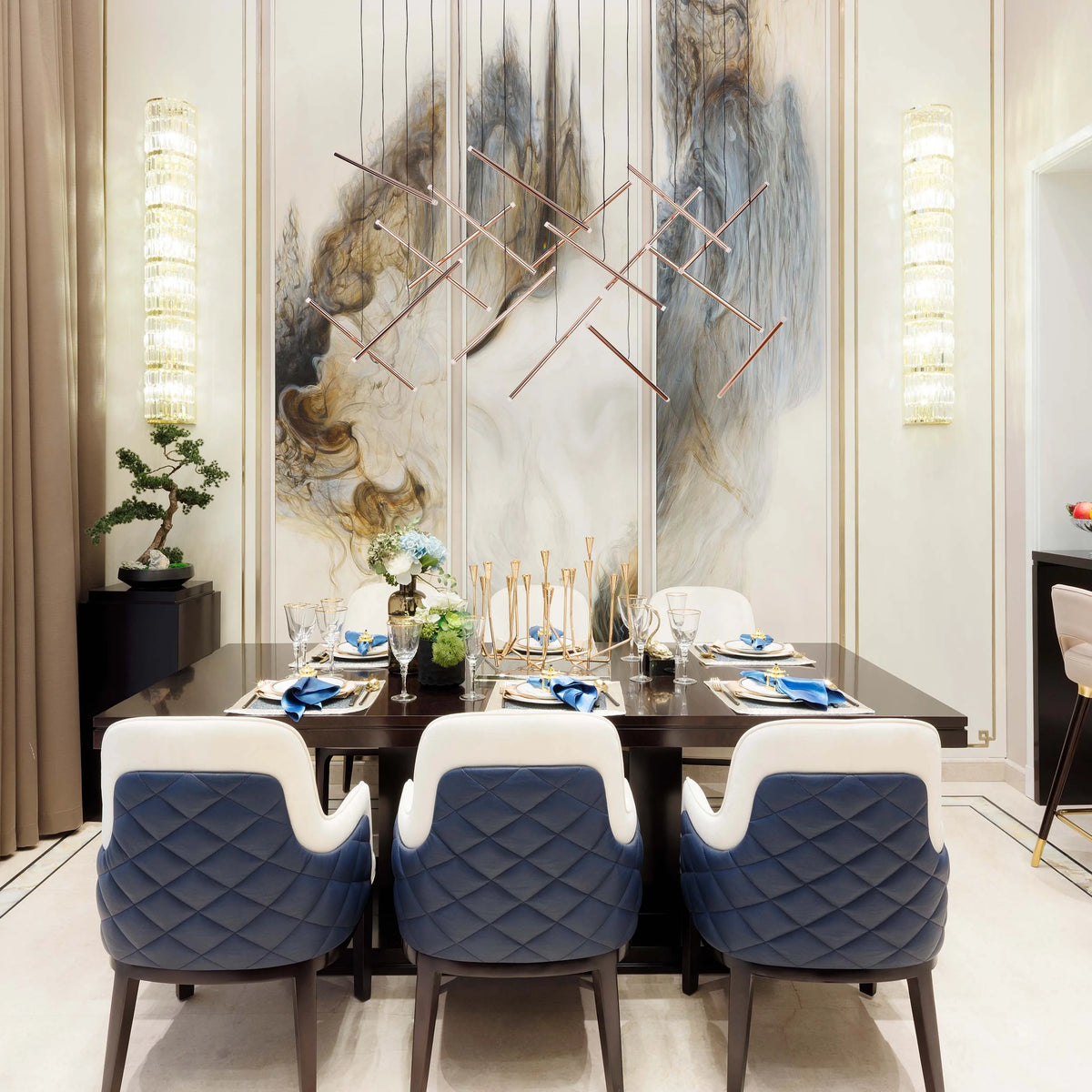 Elegant dining room with modern linear chandelier, crystal wall lights, and an art piece as backdrop. Luxurious and bright lighting.