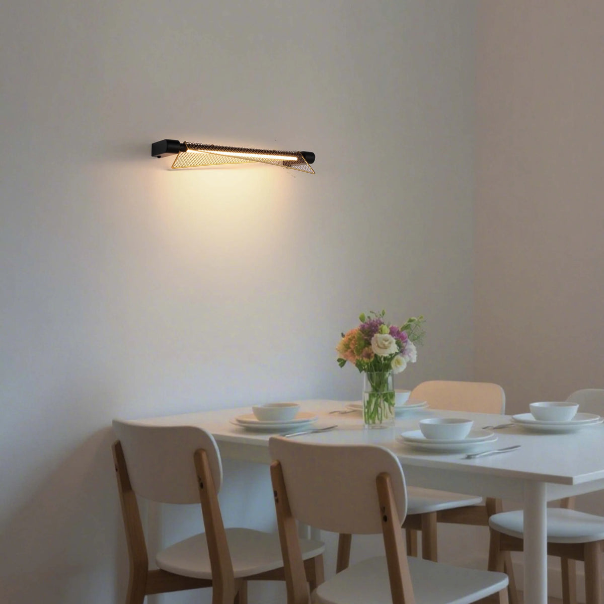 Modern wall light with a geometric, gold-tone metal shade, providing a warm glow above a dining table.
