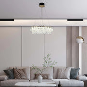 Contemporary living room showcasing a crystal chandelier, recessed lighting, and a stylish floor lamp for a modern ambiance.