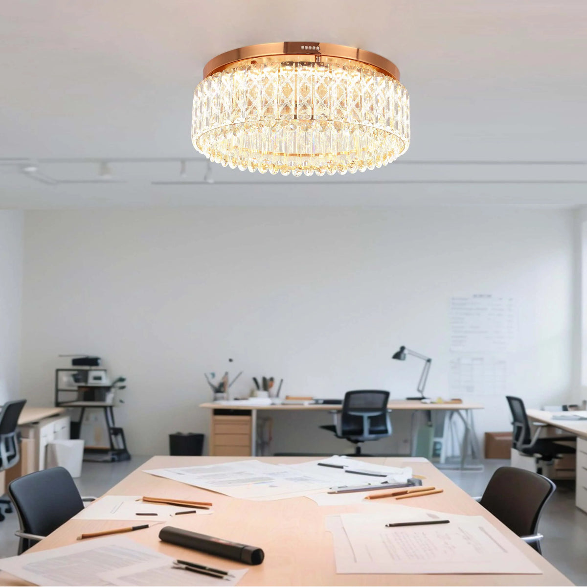 A luxurious gold and crystal chandelier illuminates a modern office space, creating an elegant and bright atmosphere.