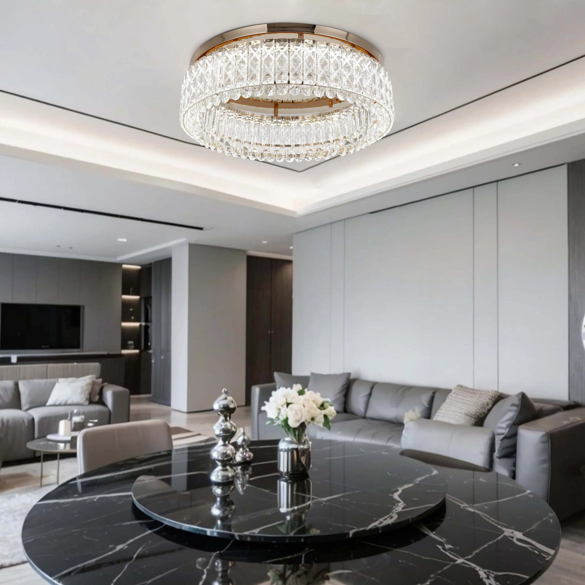 A modern living room is lit by a crystal chandelier. The light fixture is a circular, multi-tiered design.