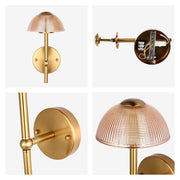 A gold coloured wall light, with a textured amber glass shade in a dome shape, attached by a gold metal rod.