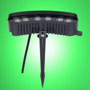 A close up of a black LED garden spotlight with a spike on a green background.
