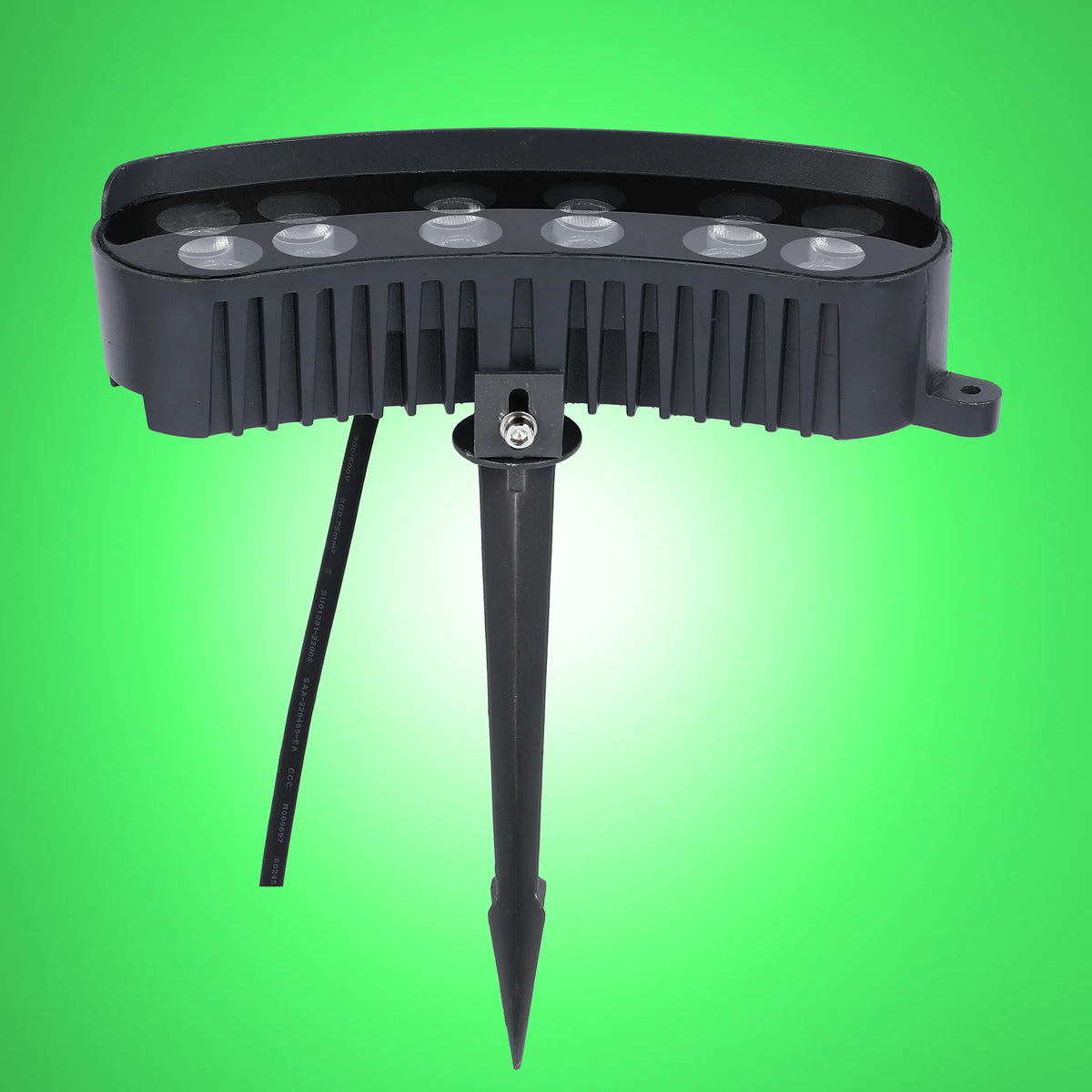 A close up of a black LED garden spotlight with a spike on a green background.